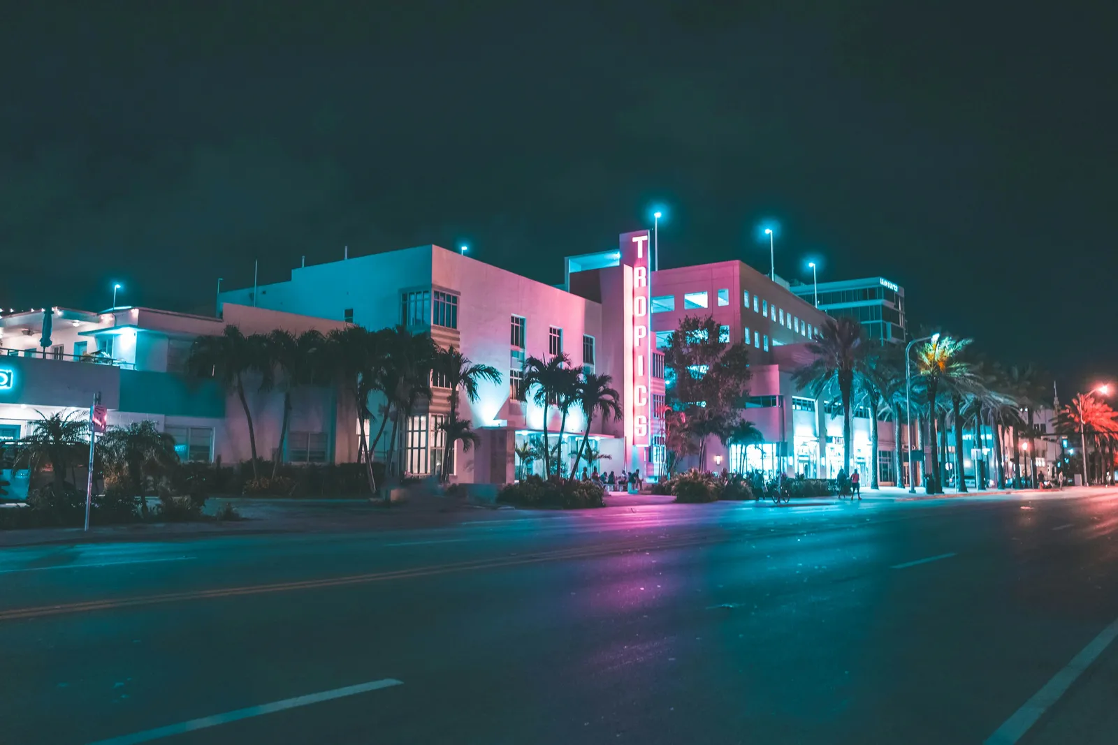 Gece Ocean Drive: palmiyelerin ardında neon tabelalı art deco otel cepheleri ve boş cadde.