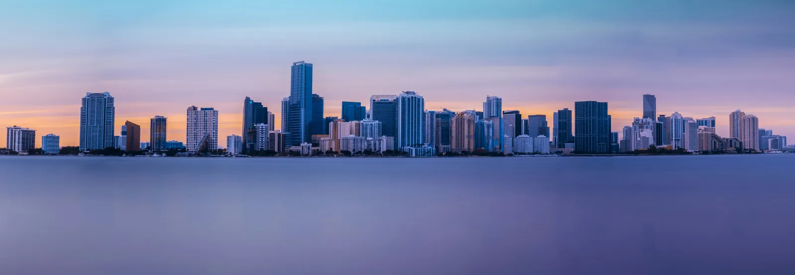Alacakaranlıkta su üzerinden görünen Miami’nin gökdelen silueti.